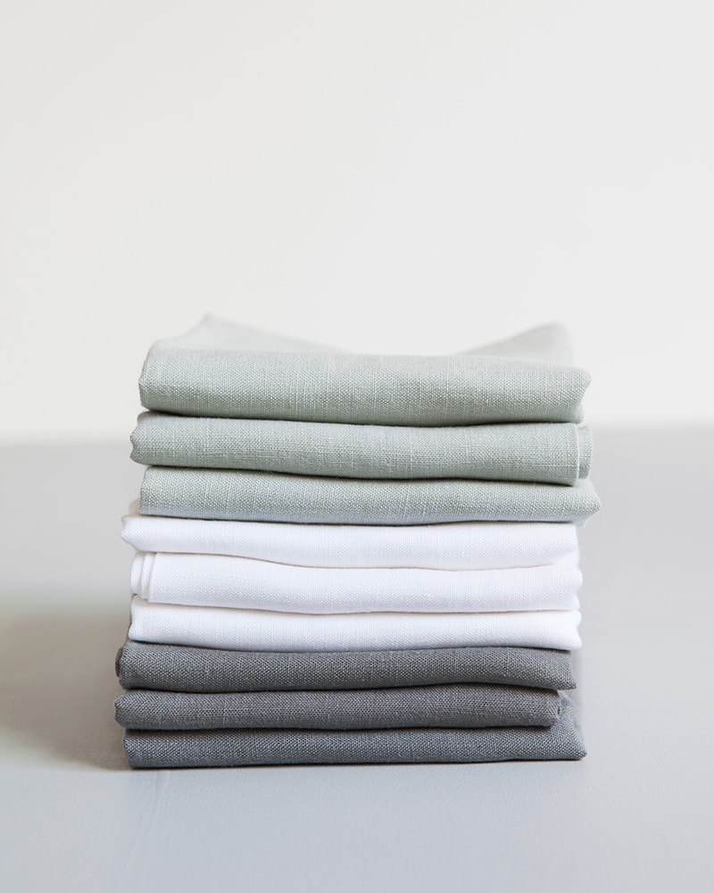 Stack of pure linen napkins come in Fumo Grey, Moon Grey and White, woven from Italian grown linen yarn at the Mungo Mill in Plettenberg Bay