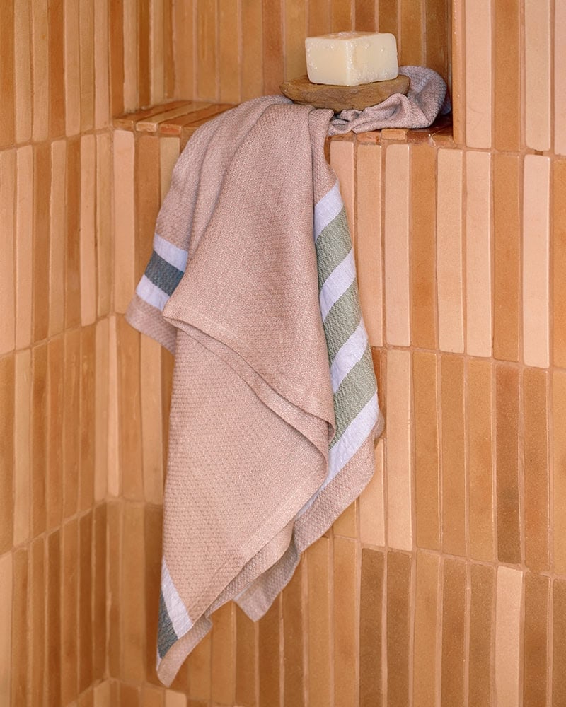 The Flax Towel, shown here in the Blossom colourway hanging in a bathroom.